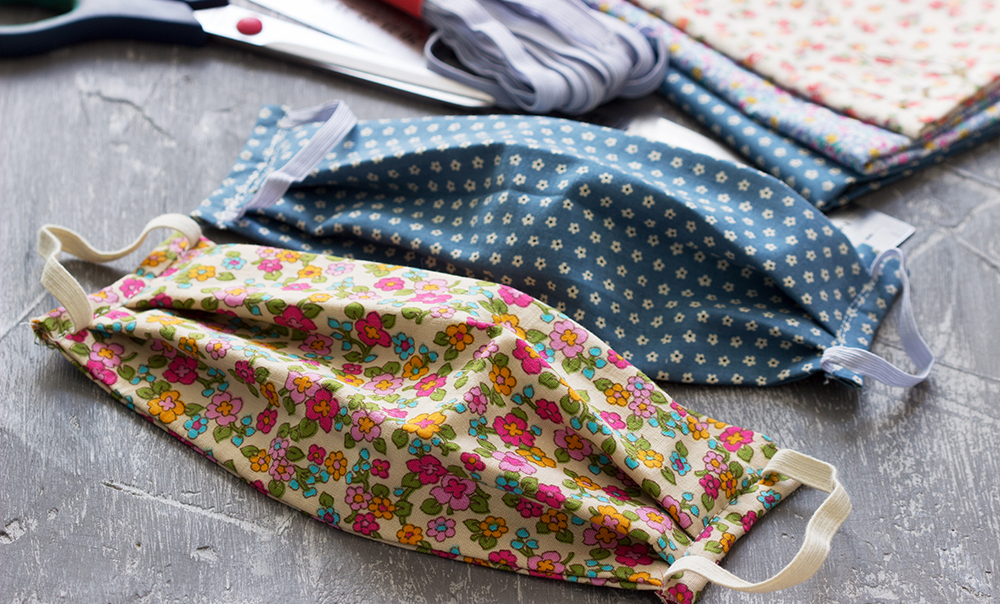 Homemade protective mask and pieces of cloth on a gray background.