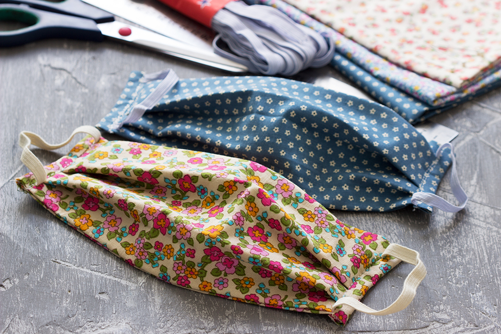Homemade protective mask and pieces of cloth on a gray background.